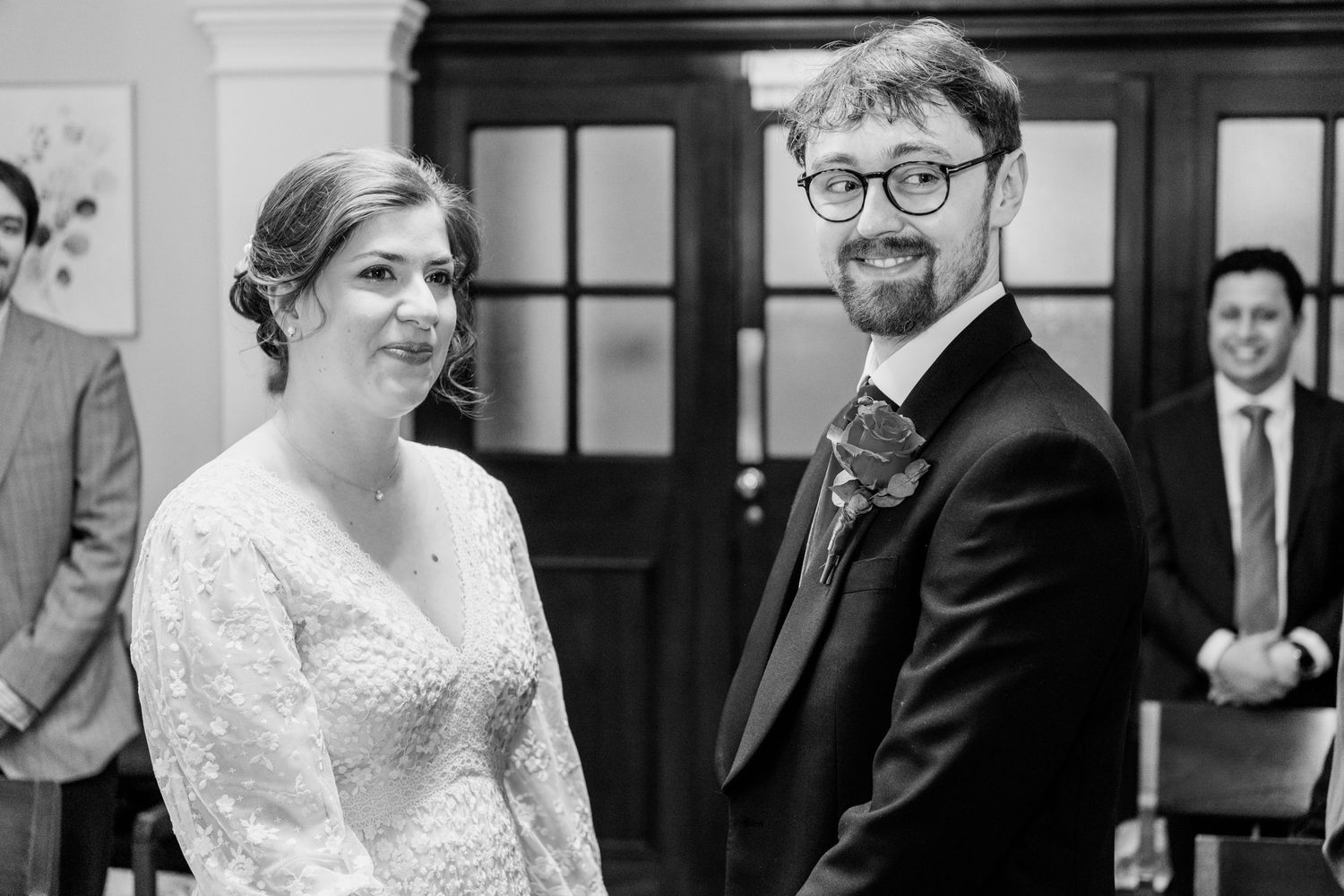 A black and white wedding photo showing a couple sharing a tender moment during their ceremony.