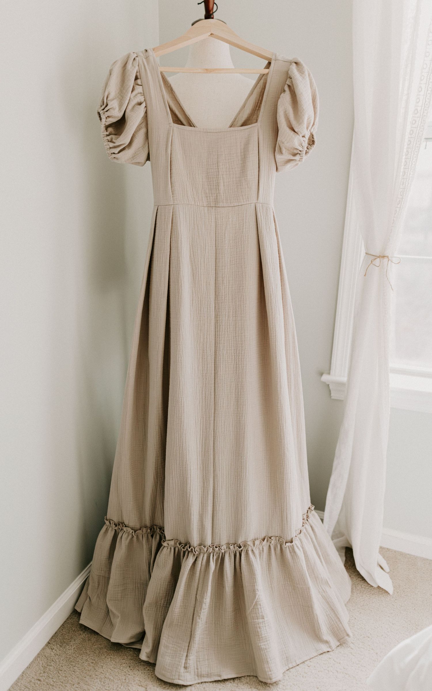 Vintage cream-colored maxi dress with puff sleeves and gathered neckline displayed on white mannequin against pale wall.
