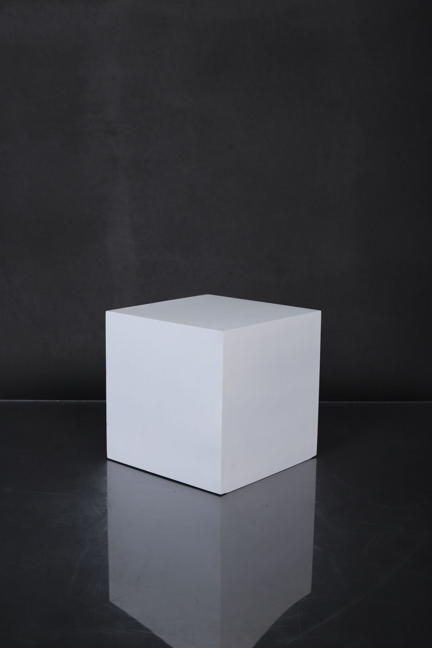 White cube on reflective black surface shown from multiple angles in minimalist studio lighting setup.
