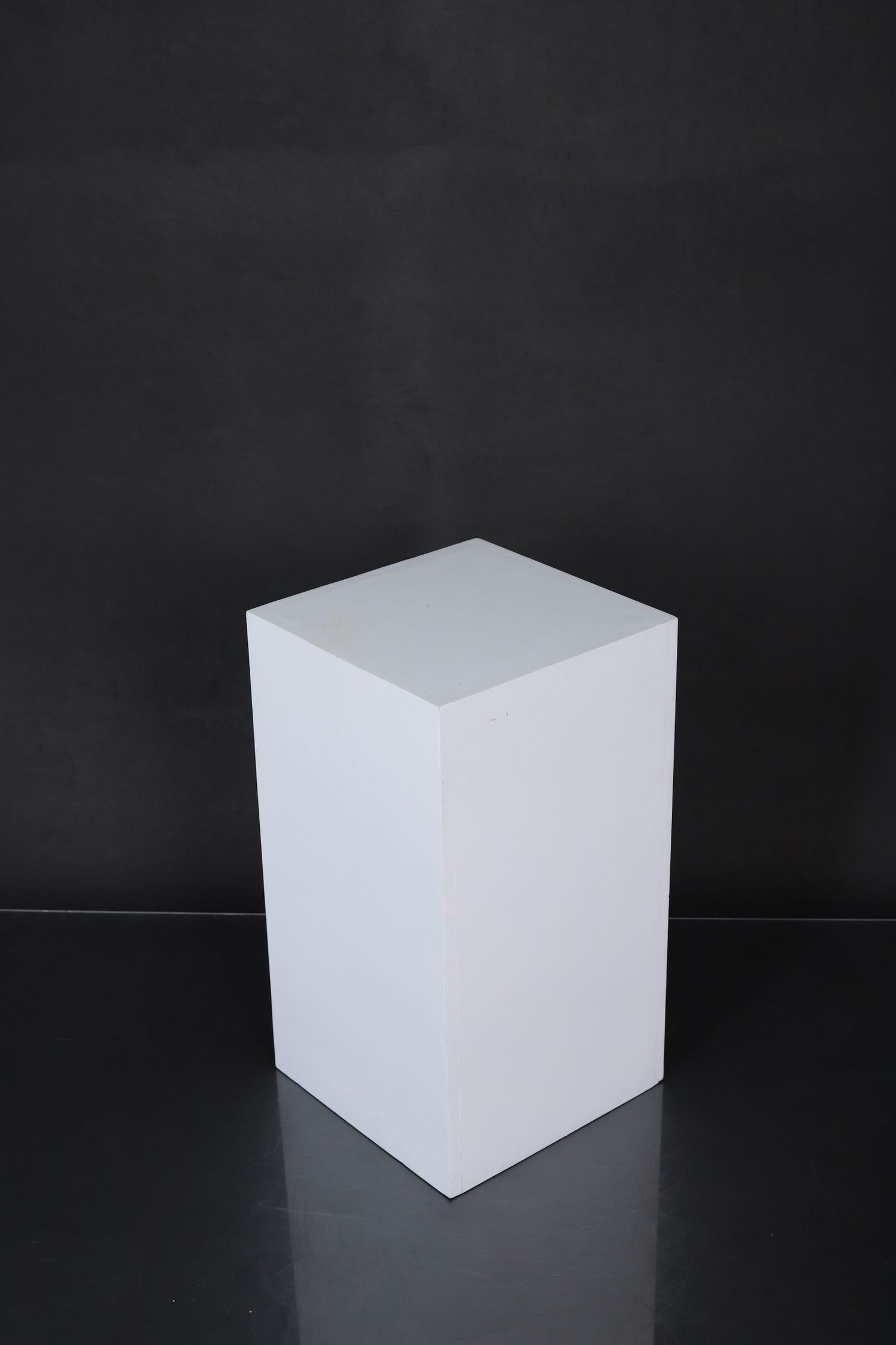 Four sequential photos show a white cube against a black background from different angles in dramatic lighting.