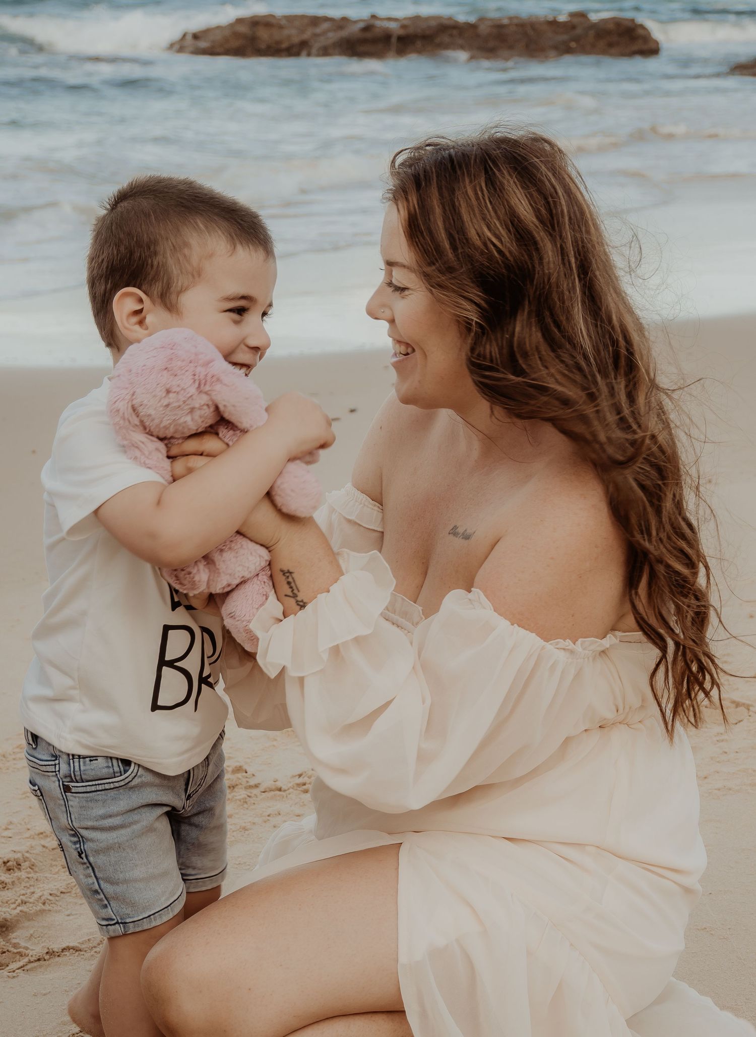Mother and toddler share joyful moments together during a beach central coast maternity photoshoot in soft lighting.