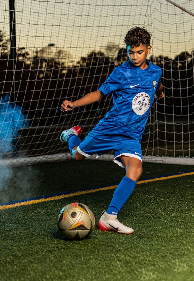 boy soccer player in willaimsburg va kicking soccer ball for a dramatic sports portrait