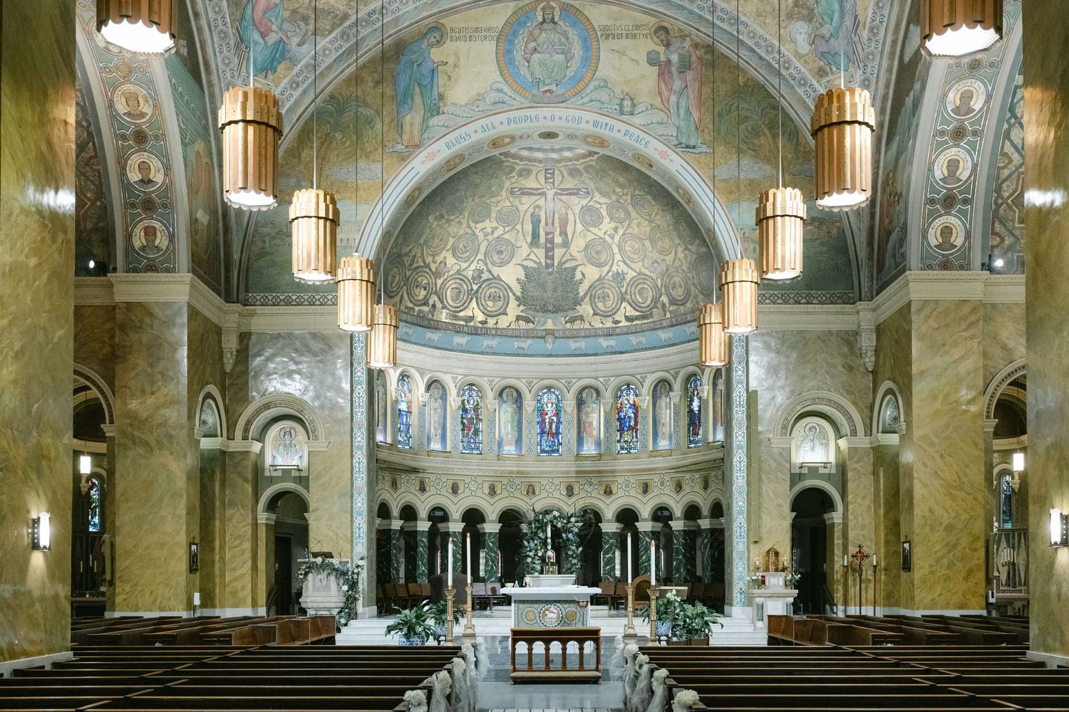 Panoramic interior view of a grand basilica with ornate mosaics, domed ceilings and marble columns.