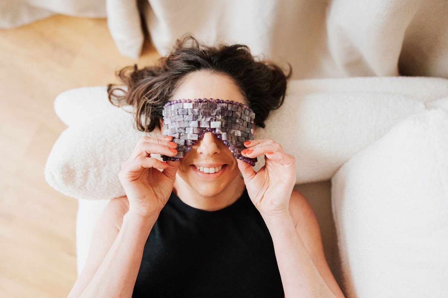 Close-up view of someone wearing sparkly sunglasses while lying on white bedding.