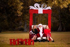 Holiday portrait setting with red gift frame backdrop and festive decorations at sunset.
