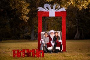 Festive outdoor photo scene with large red present frame and holiday decorations.