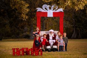 Christmas themed outdoor portrait setup featuring red gift frame and holiday decorations.
