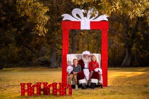 Holiday photo arrangement with bright red present frame against autumn trees.