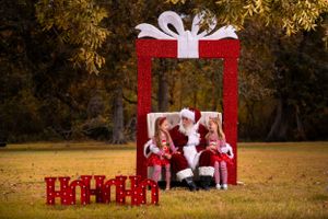 Christmas photo session with red present frame backdrop in outdoor setting.