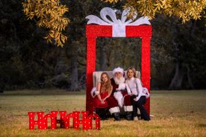 Holiday portrait setup with large red gift frame against autumn foliage.