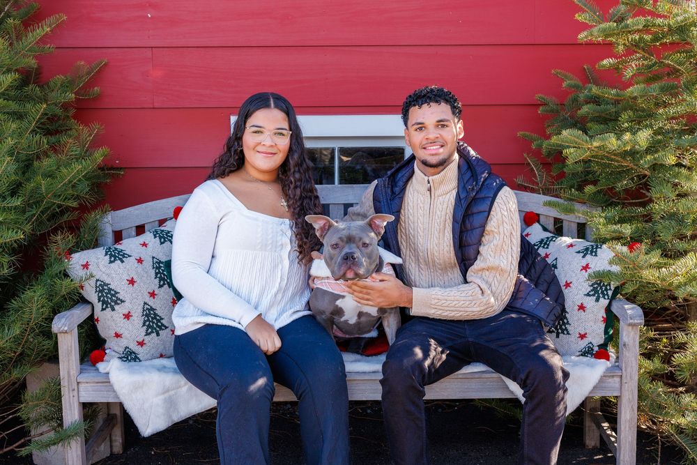 Couple sitting on red bench during outdoor photo session.