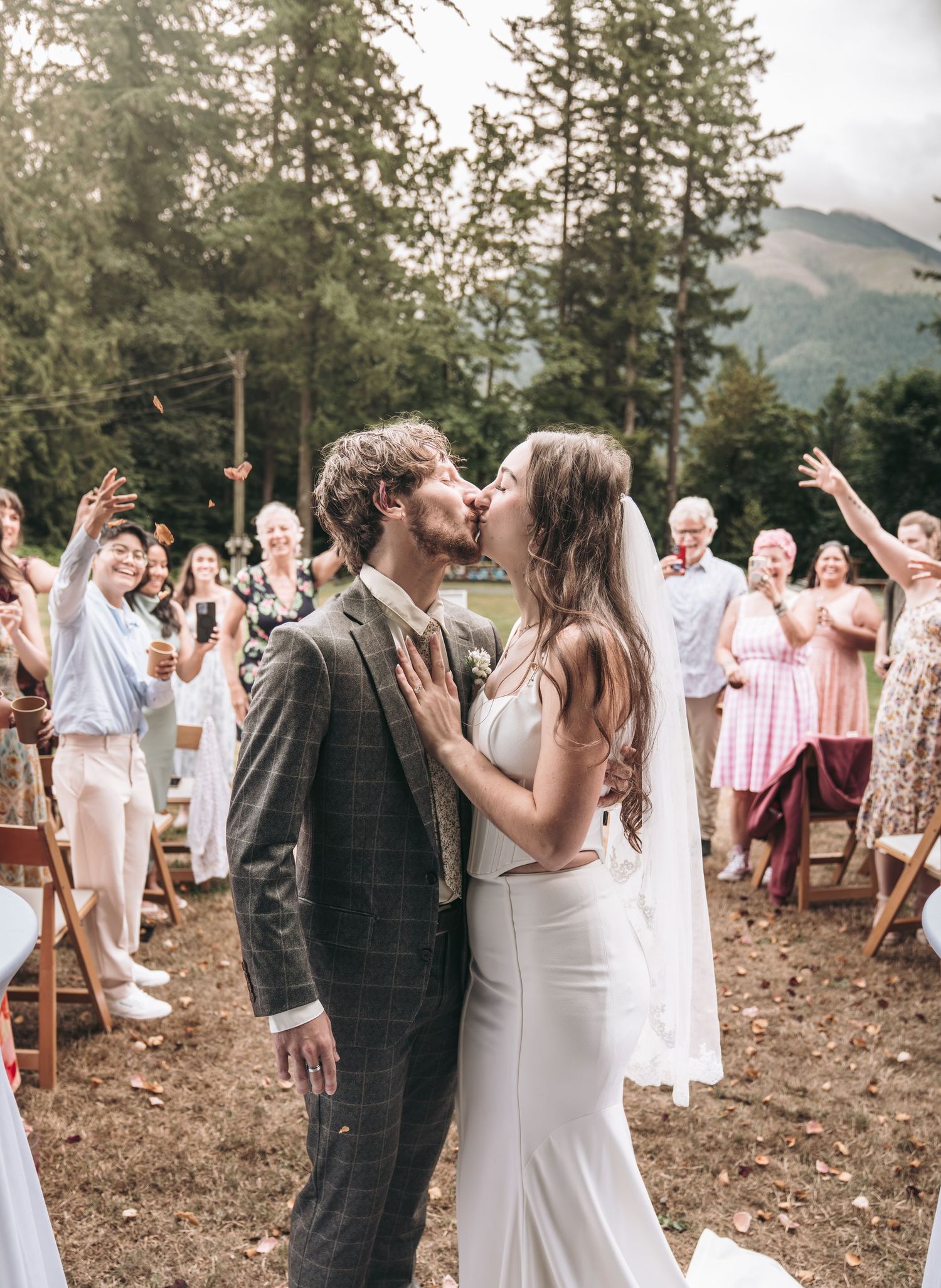 Bride in white dress placing a ring on groom's finger during outdoor garden wedding ceremony.