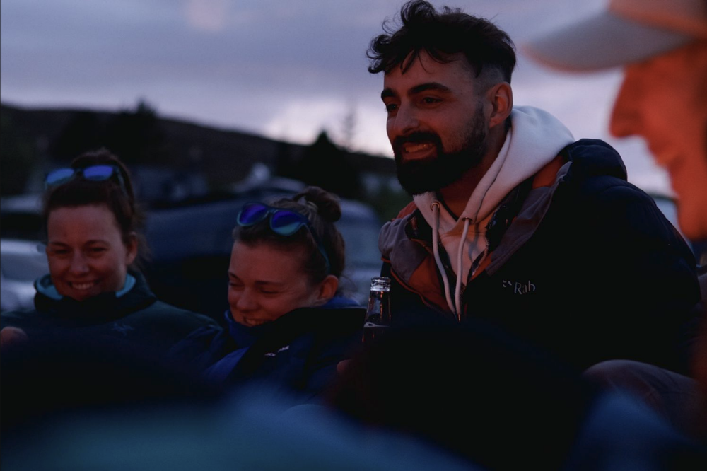 A group of people stand together at dusk in front of a dark blue sky.