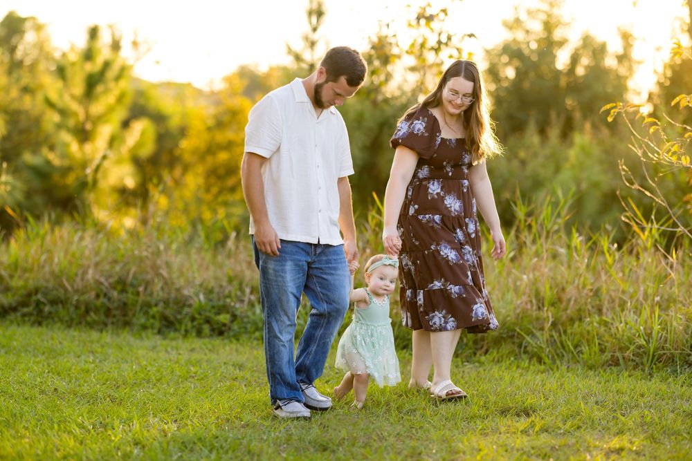 A couple stands together in a golden sunlit field during sunset creating a romantic outdoor scene.