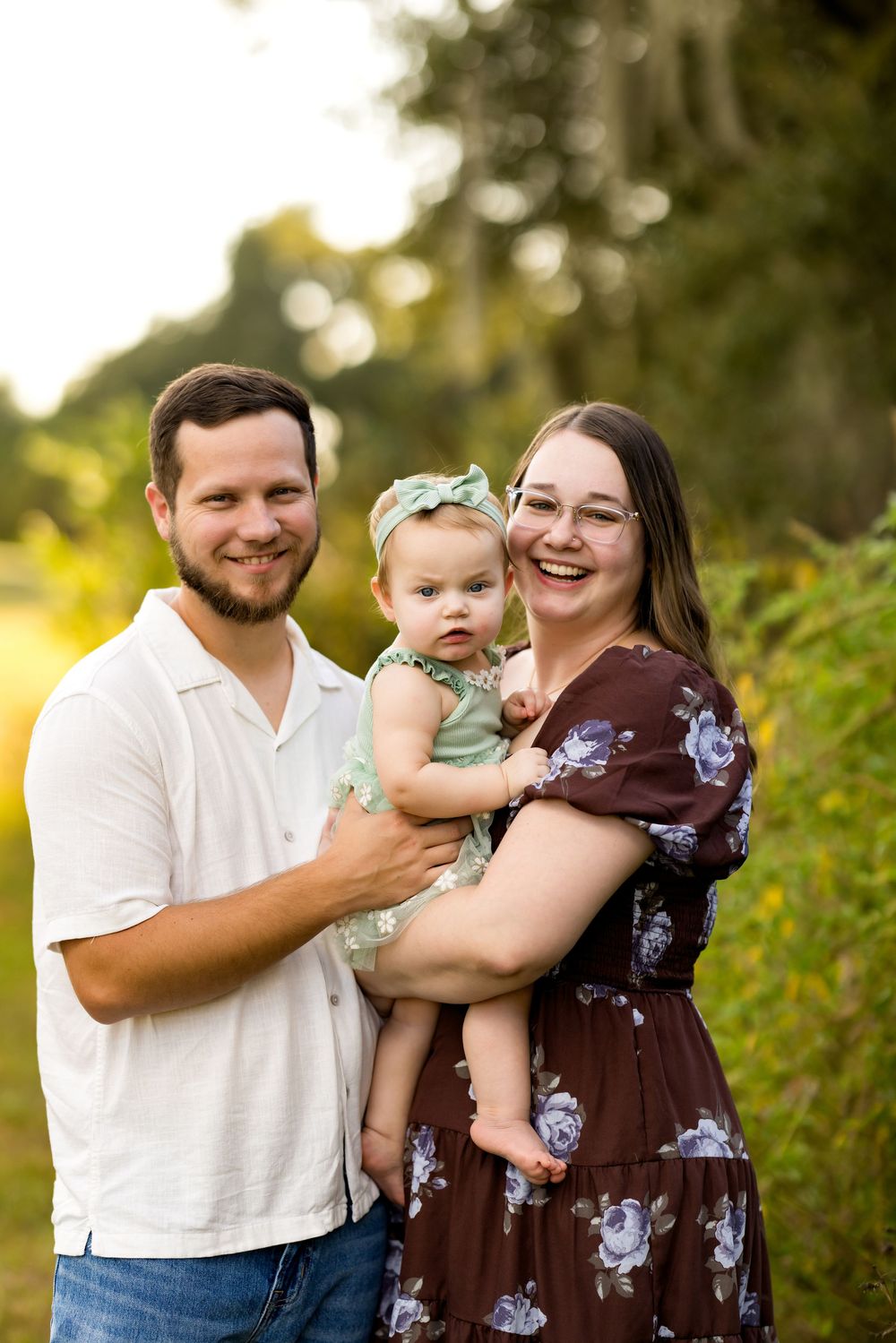 A family poses together outdoors in a natural setting during golden hour.