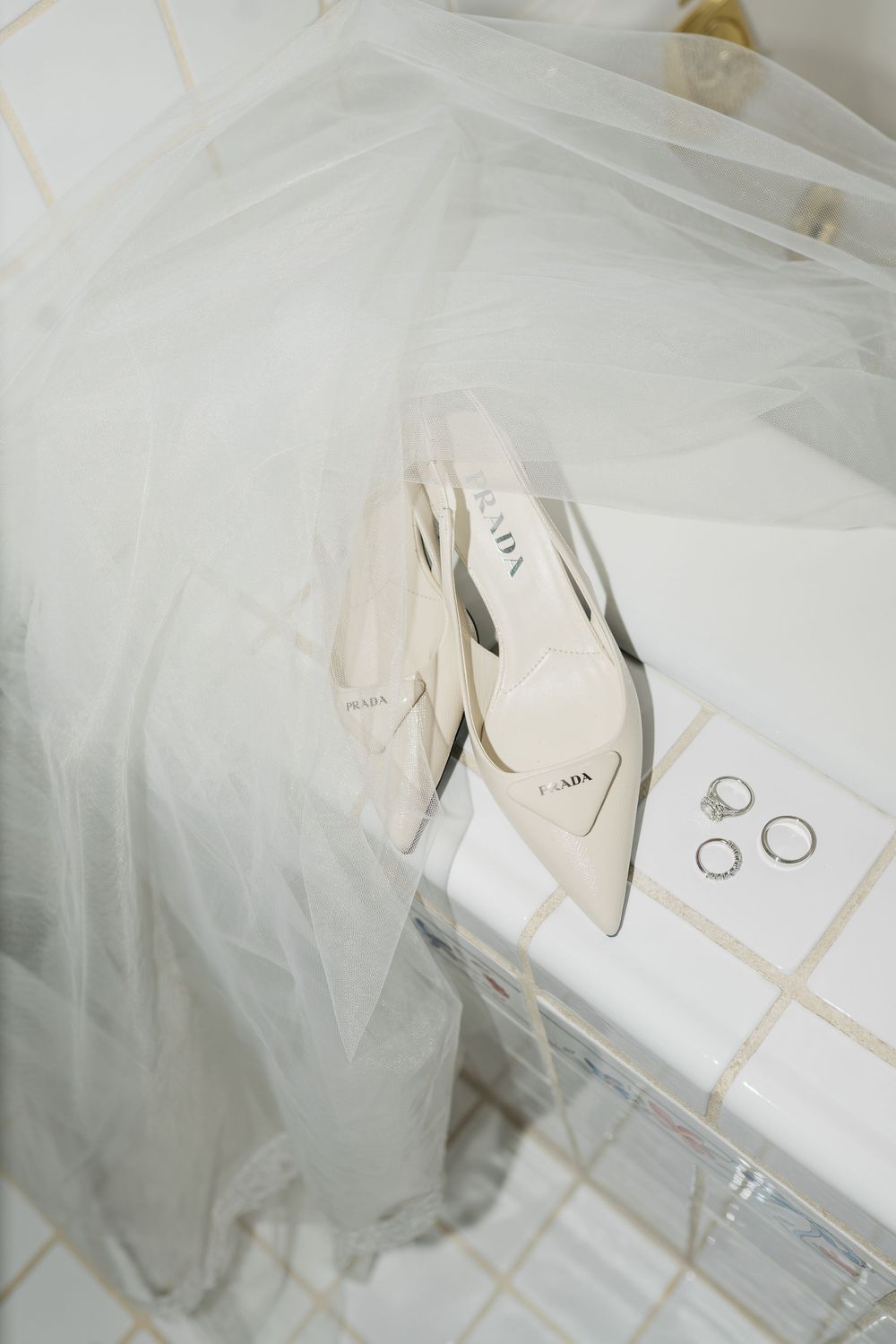 Delicate white tulle veil and wedding accessories arranged on a light surface.