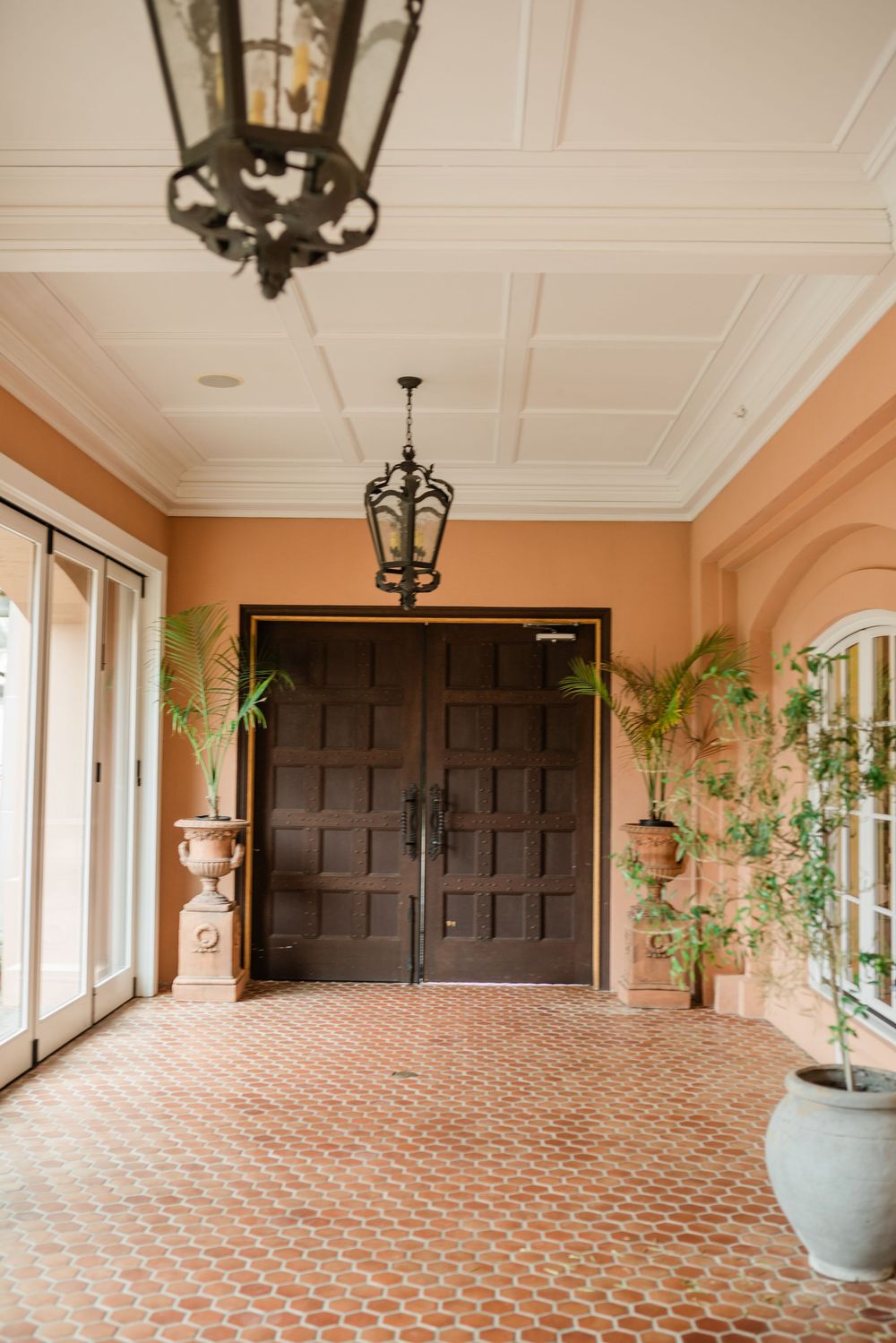 Elegant hallway with peach walls, patterned tile floor and hanging lantern fixtures.