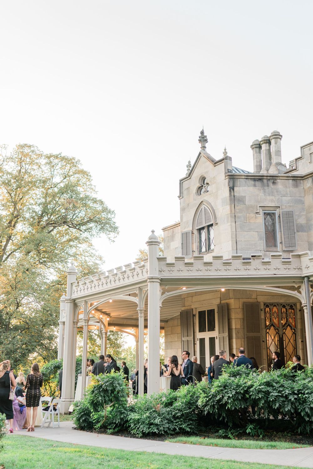 Gothic revival stone mansion with arched windows and covered portico serving as wedding venue.