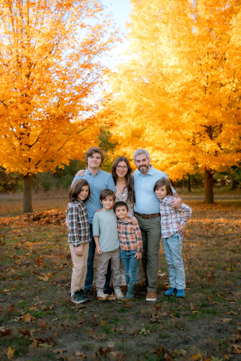 A group portrait against a stunning backdrop of golden fall foliage in a park setting.