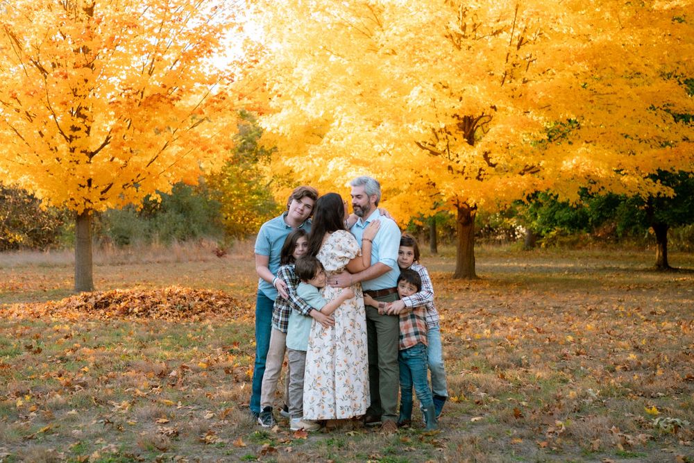 Scenic autumn landscape with people gathered under bright orange maple trees.