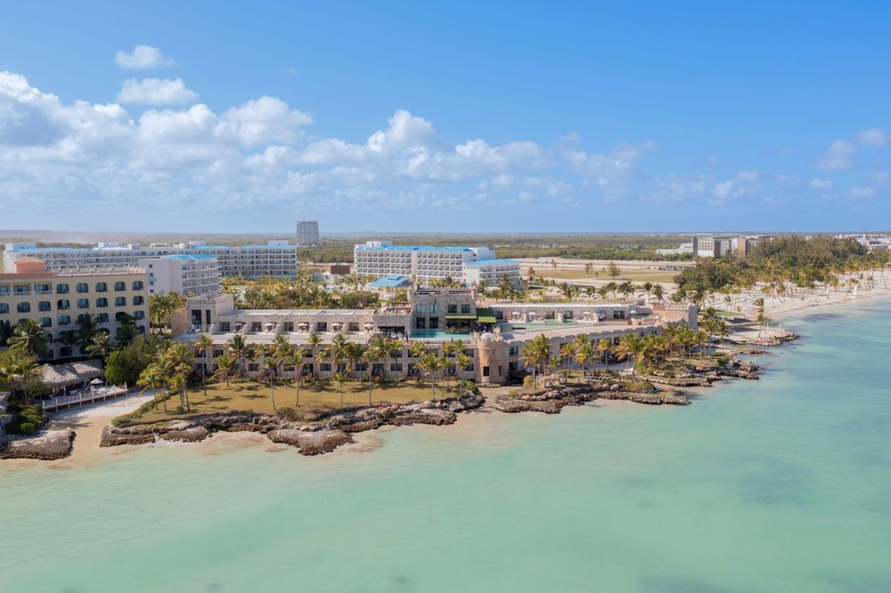 Aerial panoramic view of a beachfront resort with turquoise waters and sandy beaches.
