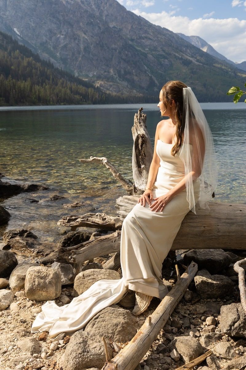 Wedding photos captured along a rocky lakeshore with dramatic mountain scenery and blue skies.
