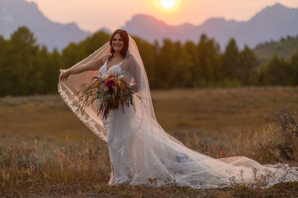 Sunset wedding photography session in an open field with silhouetted mountains creating a dreamy backdrop.