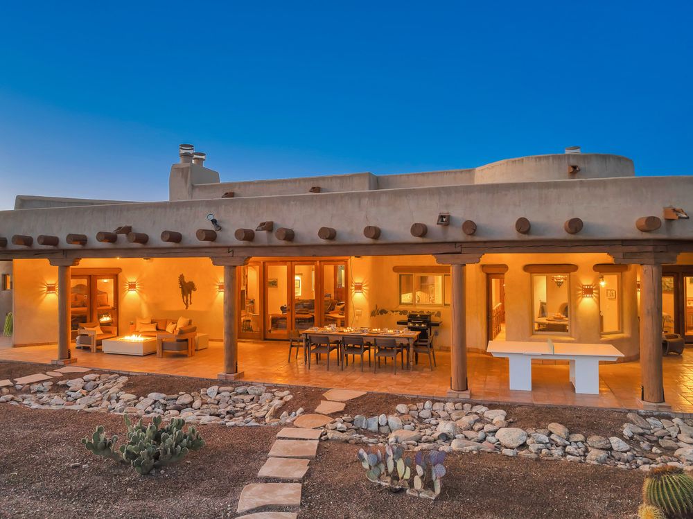 A panoramic view of a luxury desert resort with adobe-style buildings and outdoor seating areas at sunset.