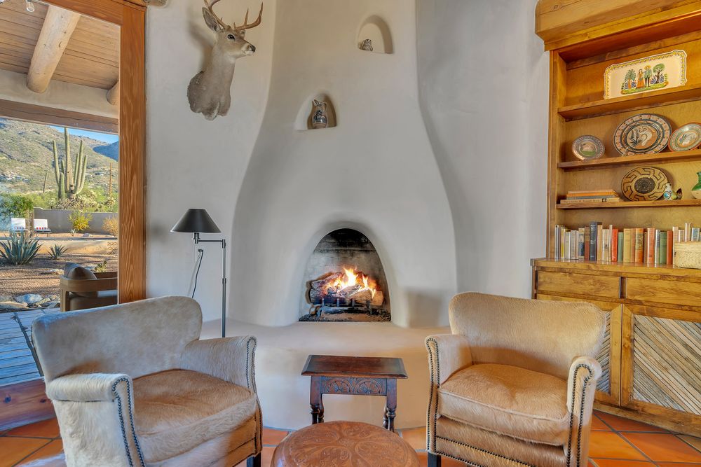 Interior of a rustic cabin with adobe walls, wooden beams, and southwestern decor featuring antler mounts and woven textiles.