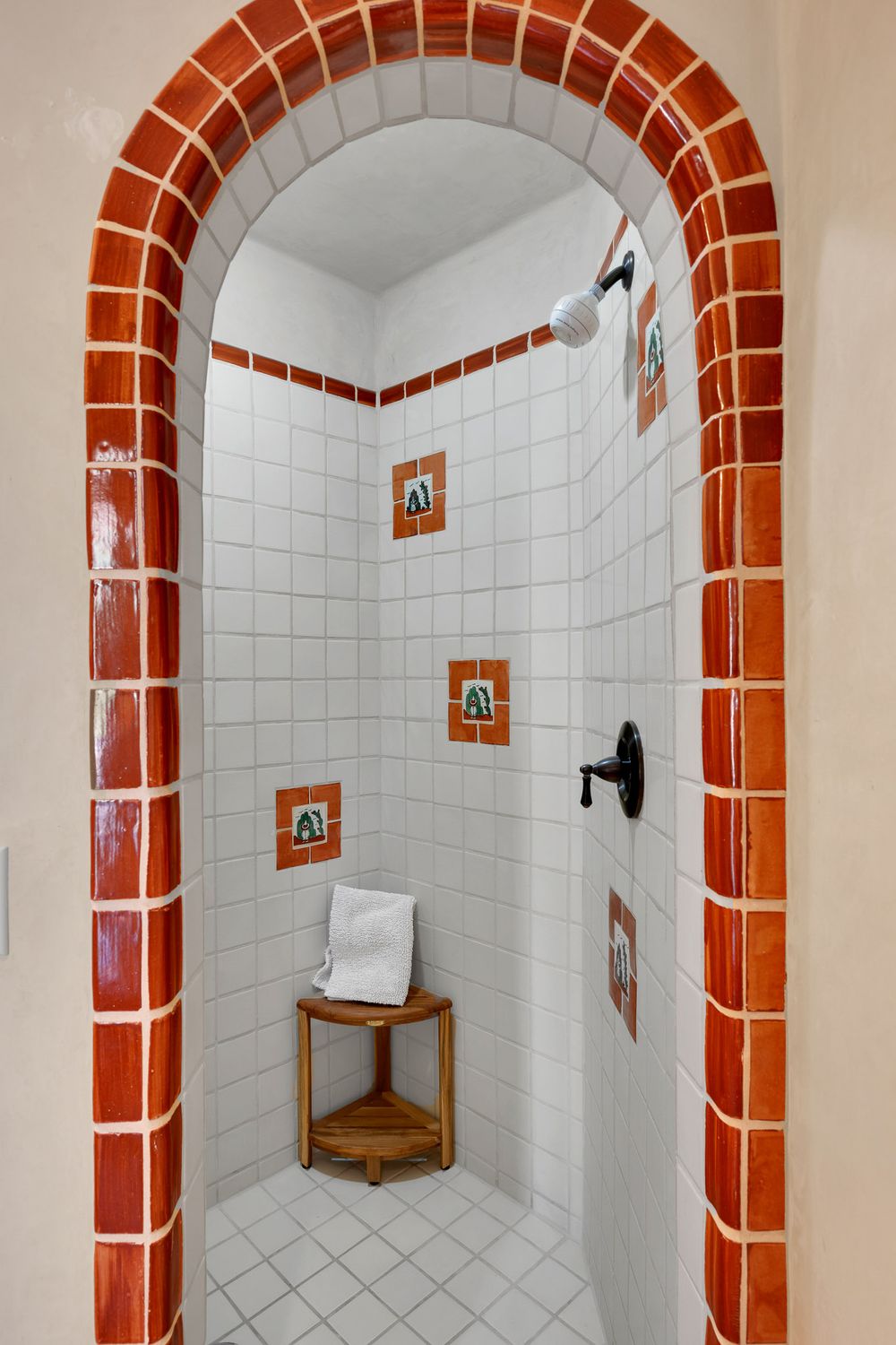 White tiled bathroom with distinctive terracotta-colored archways and small decorative wall niches in Mexican style.