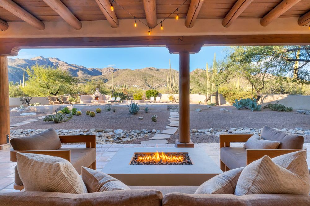 Luxury patio with fire pit and mountain views through wooden beams and comfortable outdoor seating.