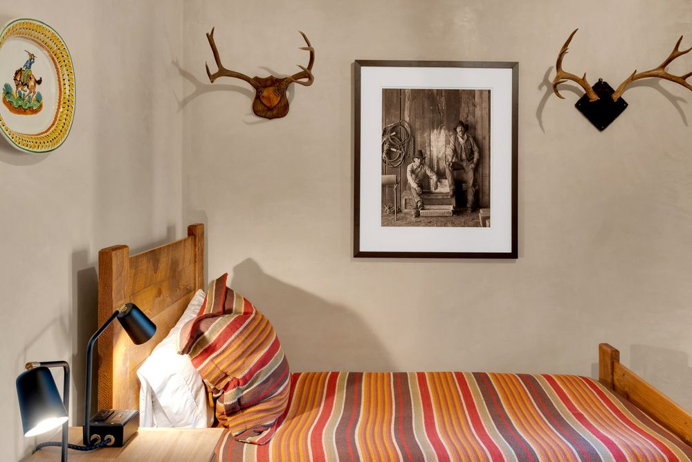 Rustic bedroom decor featuring mounted antlers, a framed black and white photograph, and a striped bedspread.