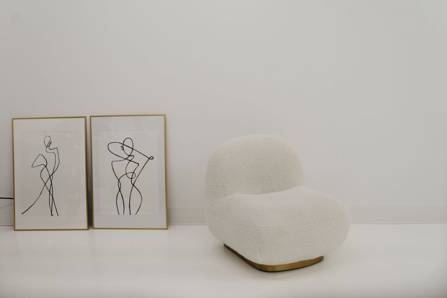 Minimalist line drawings and abstract artwork displayed in white frames against a neutral wall.