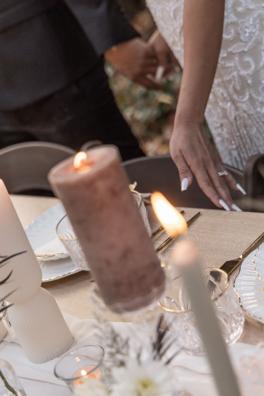 Elegant place settings and candles on a white tablecloth at a formal dining event.