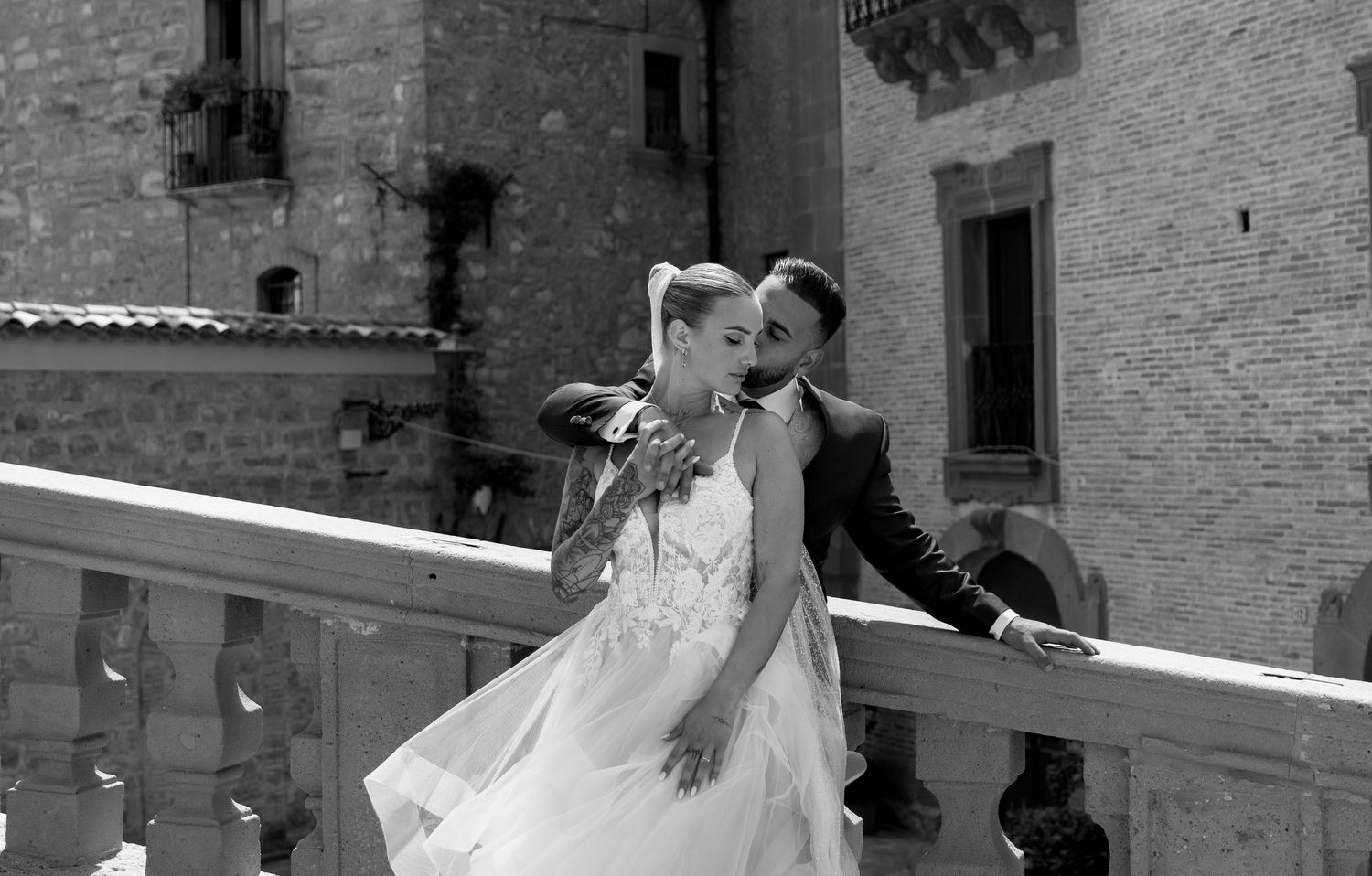A wedding party celebrates in a rustic stone courtyard with joyful dancing and movement.