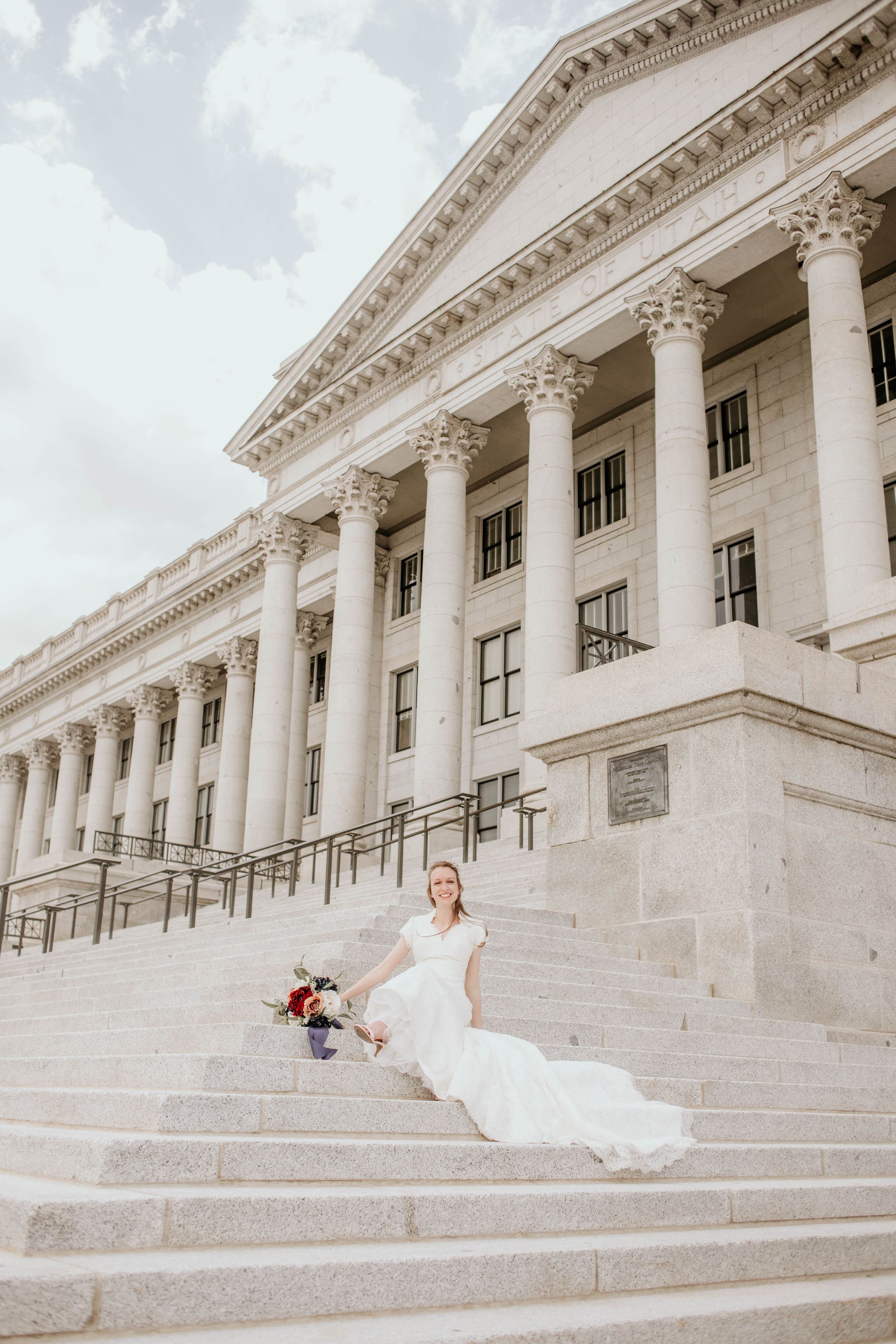 A sequence of wedding photos showing a couple laying playfully on the grand stone steps of a neoclassical government building.