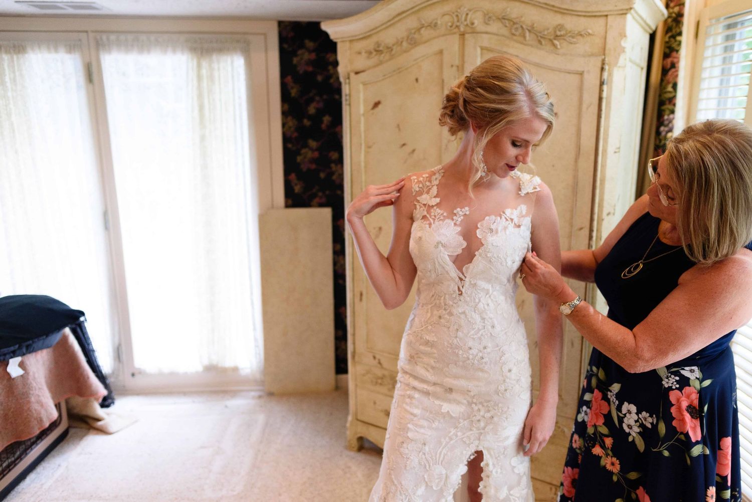 Mother of the bride helping her daughter into her wedding dress