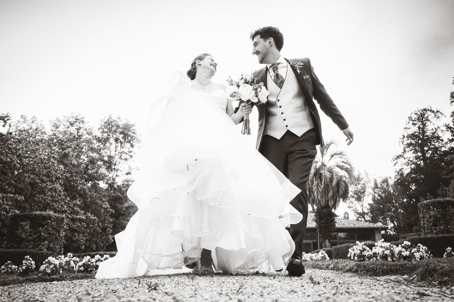 Novios caminando y riendo durante su boda al aire libre, fotografía documental de boda en Asturias con un momento natural y espontáneo.