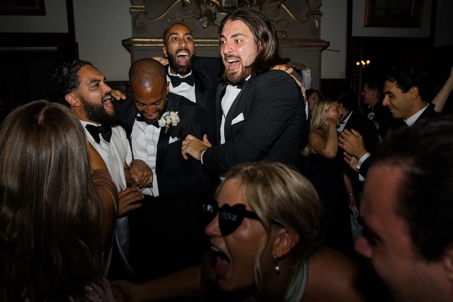 A group of people enjoying themselves at a dark indoor social gathering or party.