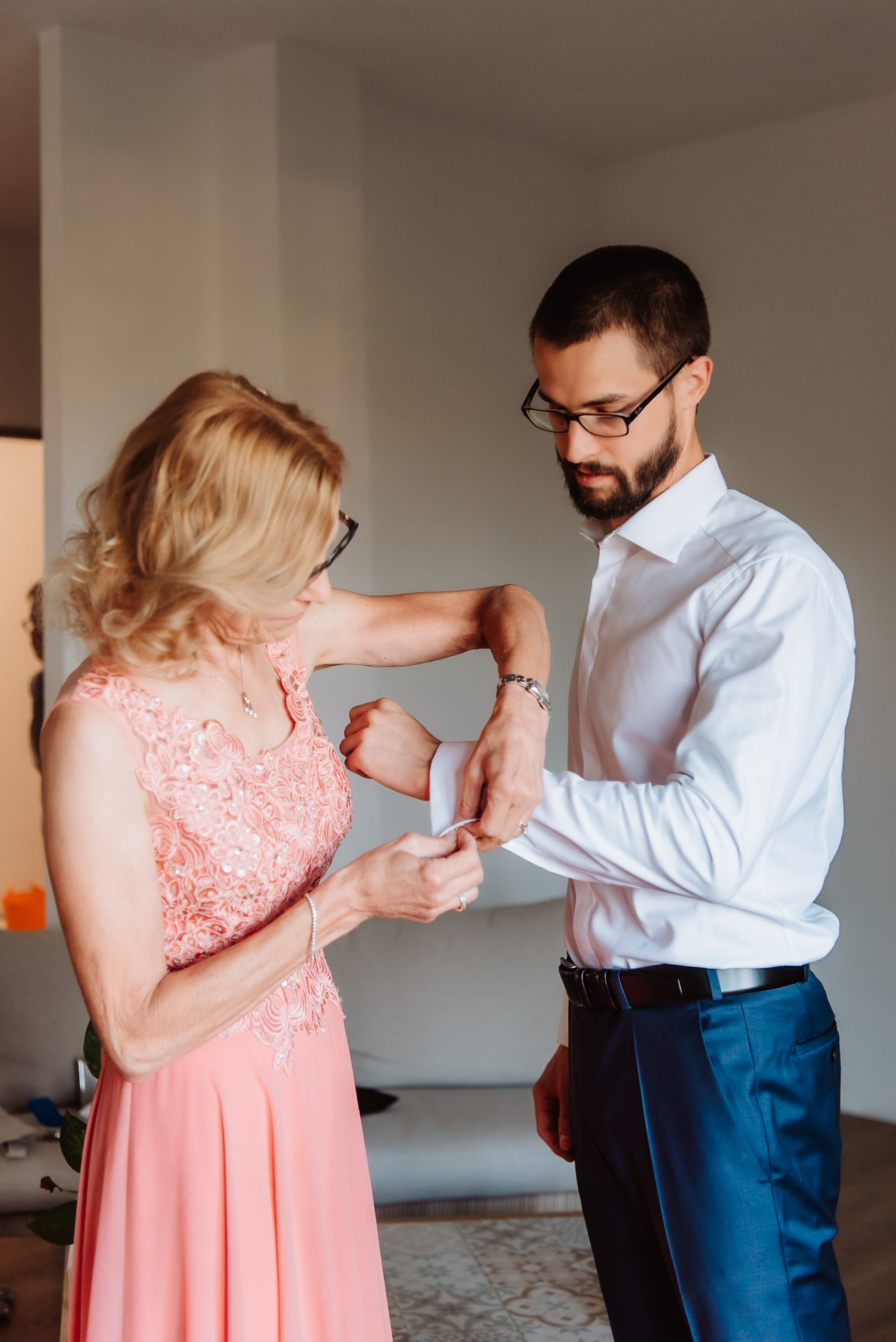 Wedding preparations showing someone adjusting formal attire in a pink lace dress.