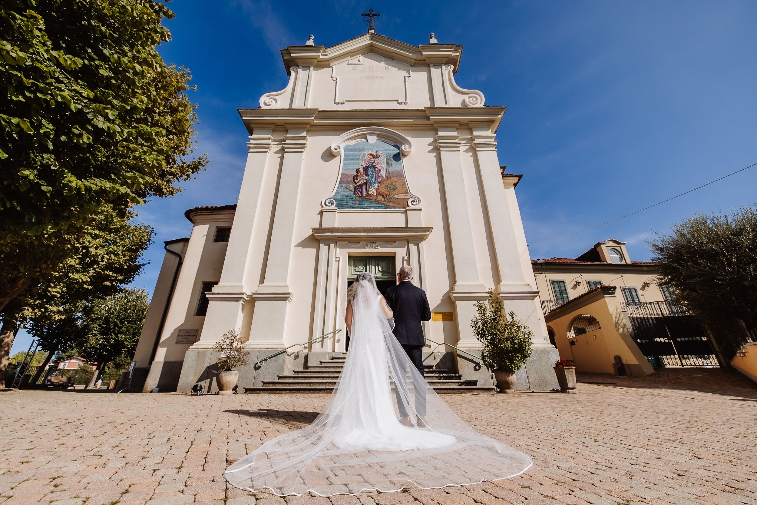 Panoramic sequence of a traditional white Italian church exterior with classic architectural details and cypress trees.
