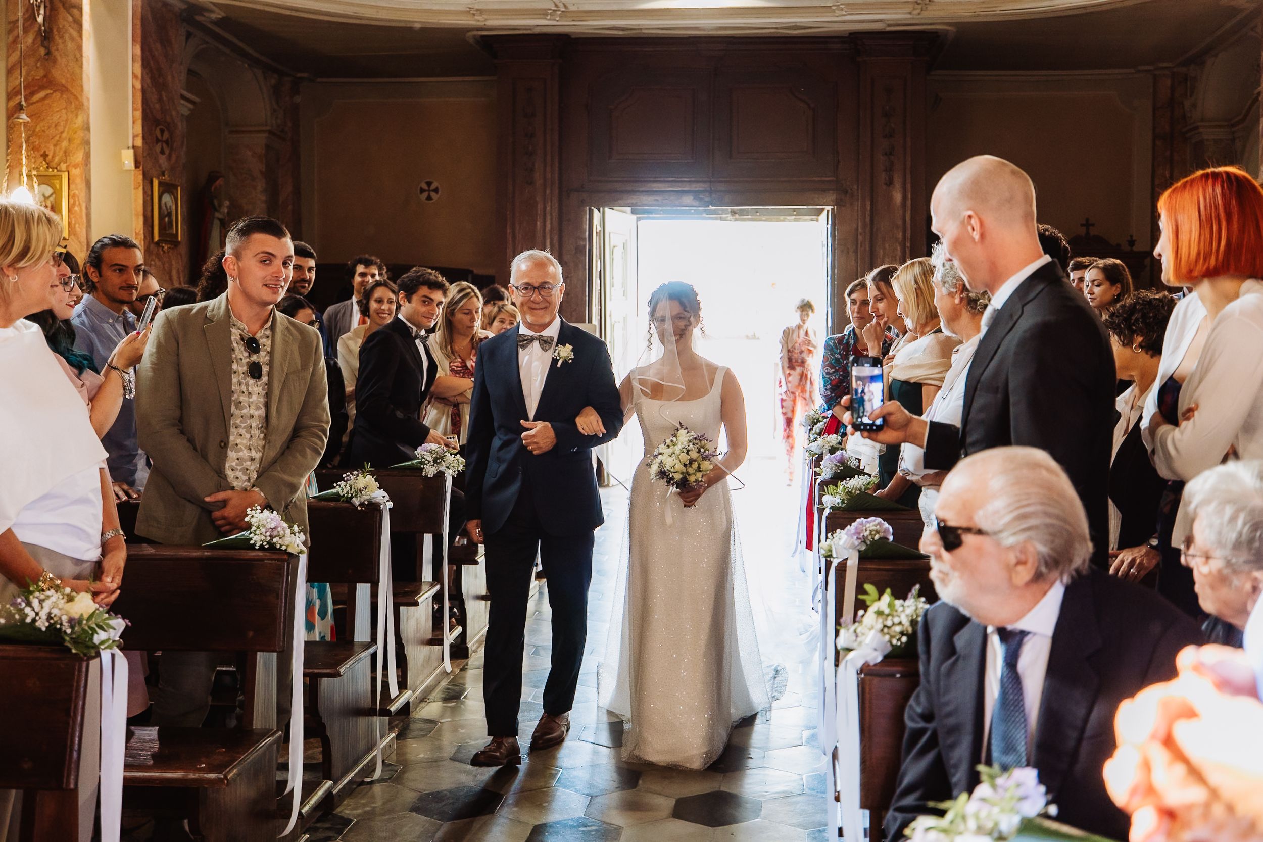 Wedding guests line both sides of an elegant hallway to celebrate as a couple makes their grand exit.