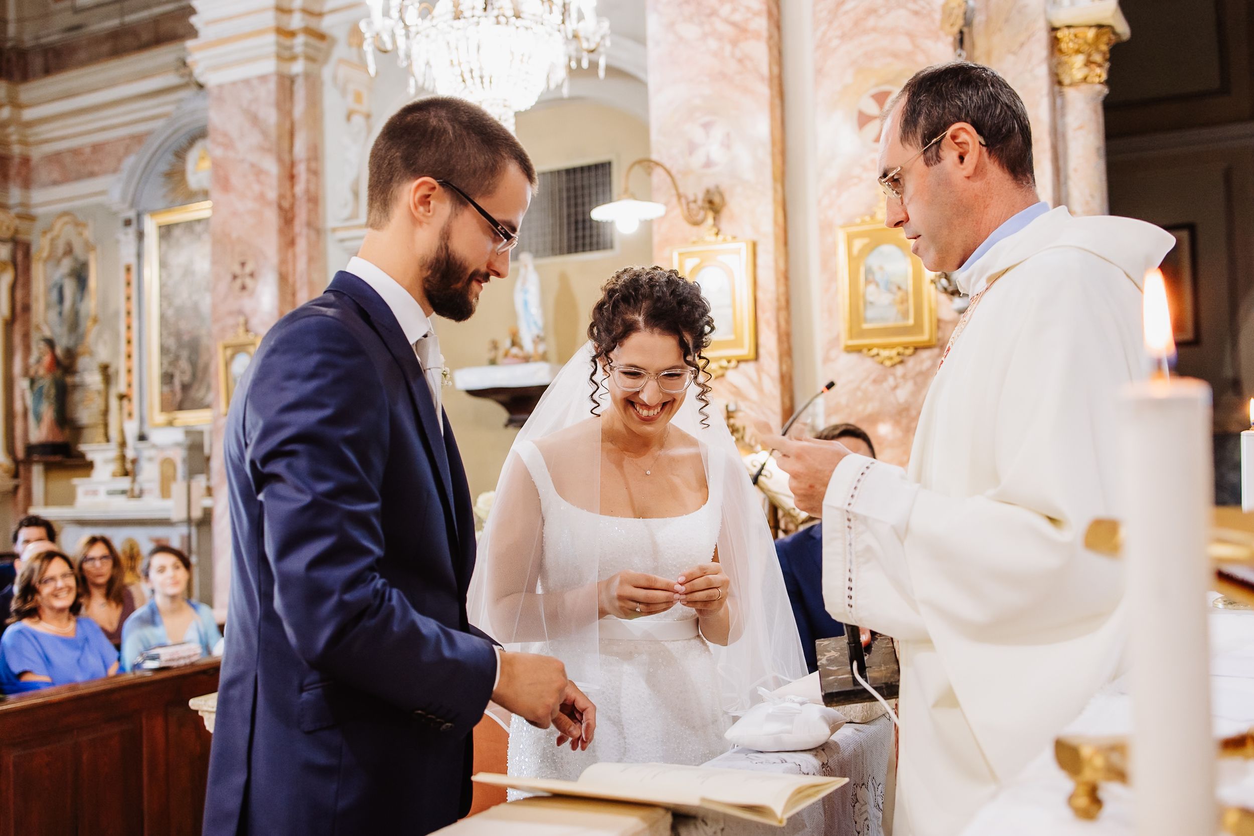 A couple shares an intimate moment during their wedding ceremony in an ornate church setting.