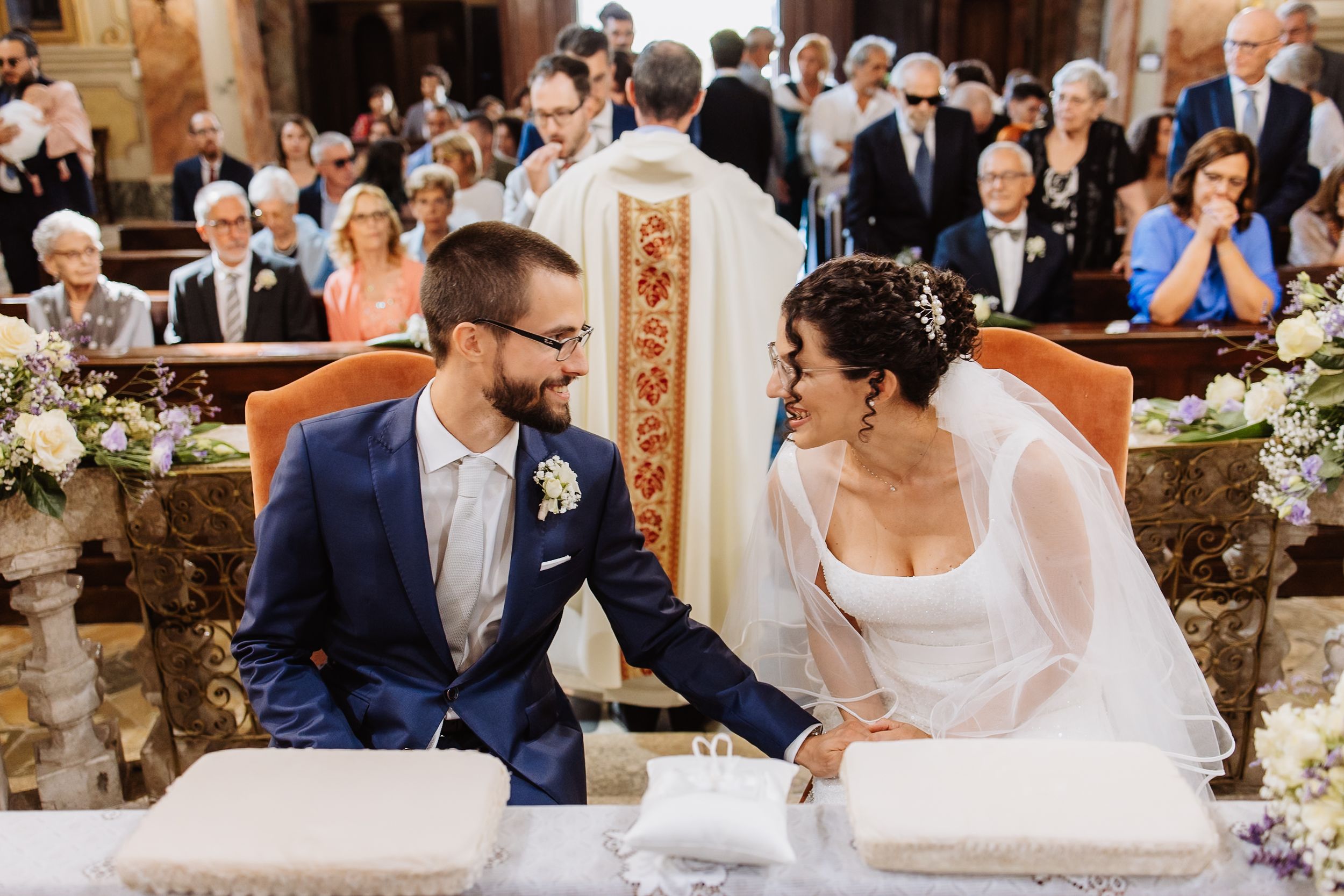 A romantic wedding ceremony unfolds in an ornate church with guests watching the couple exchange vows.