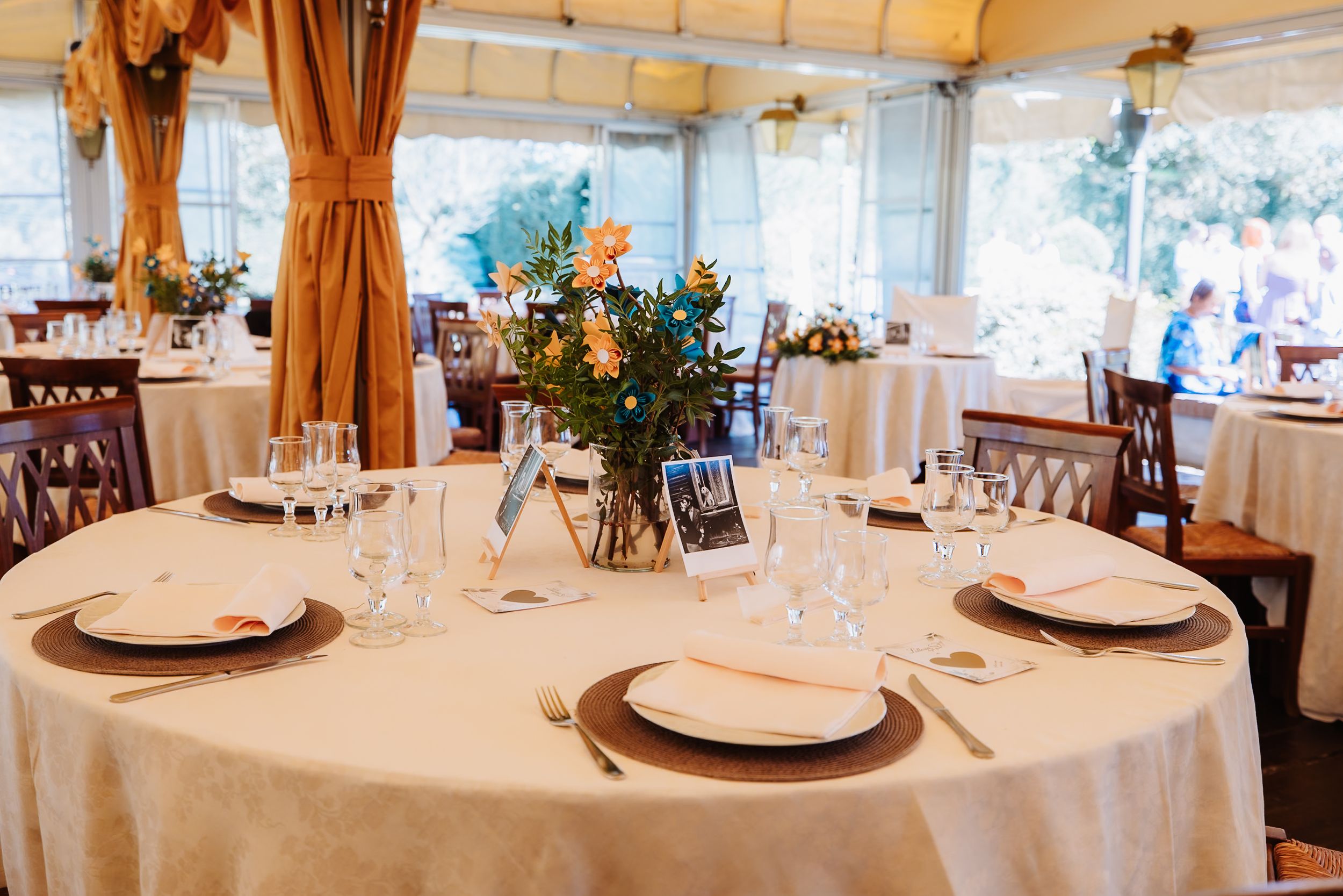 A panoramic view of an elegant white dining room with round tables set for a formal event or wedding reception.
