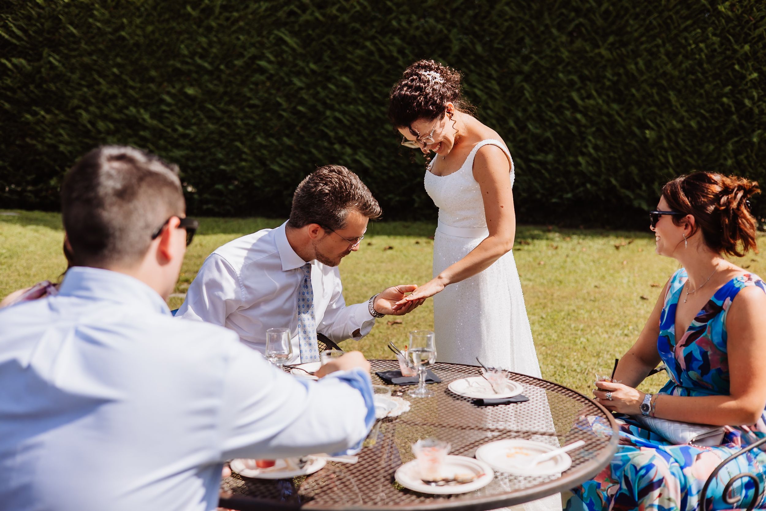 People enjoying a casual outdoor dining gathering at a long table in a garden setting.