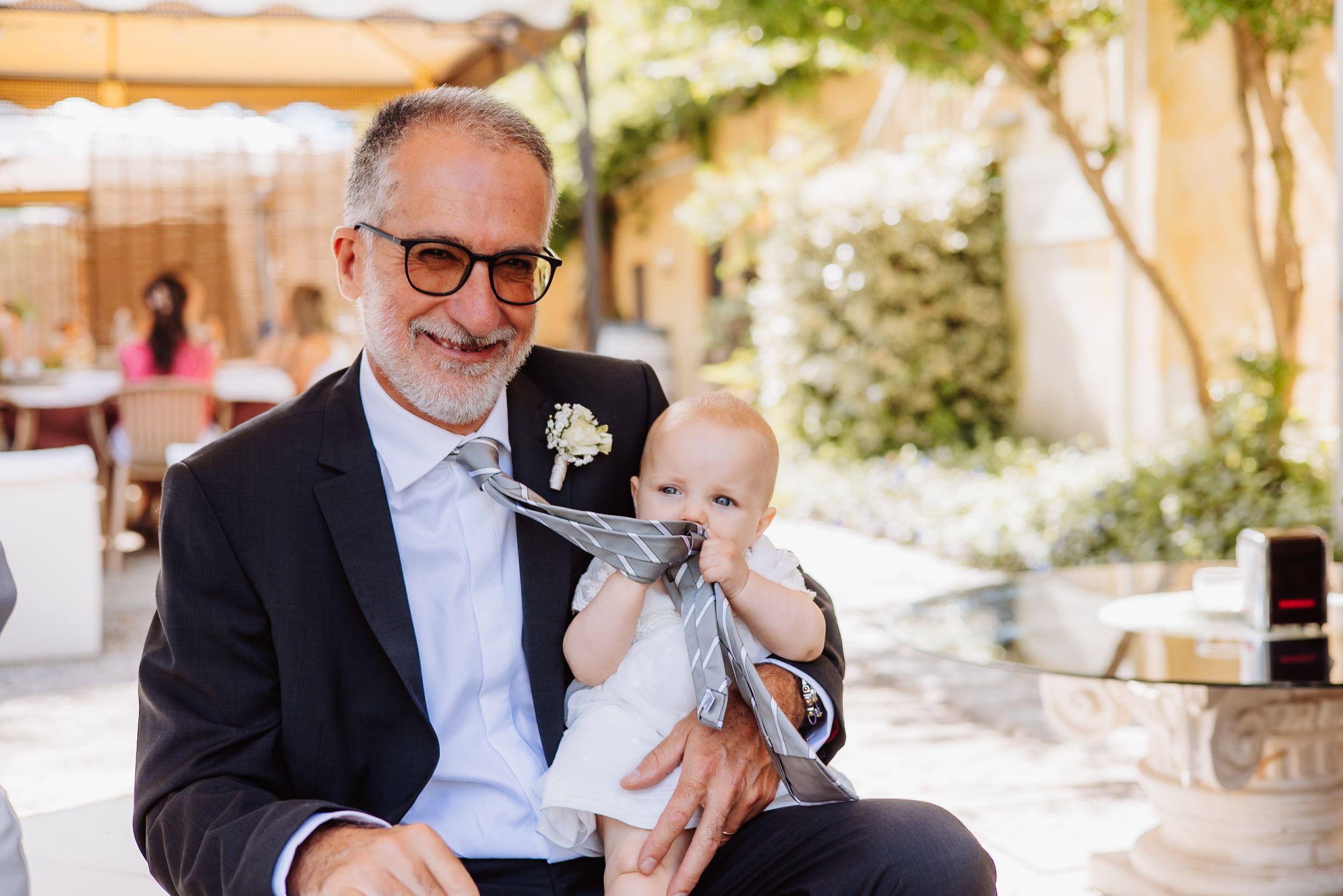 Wedding celebration in a Mediterranean courtyard setting with guests gathering under trees.