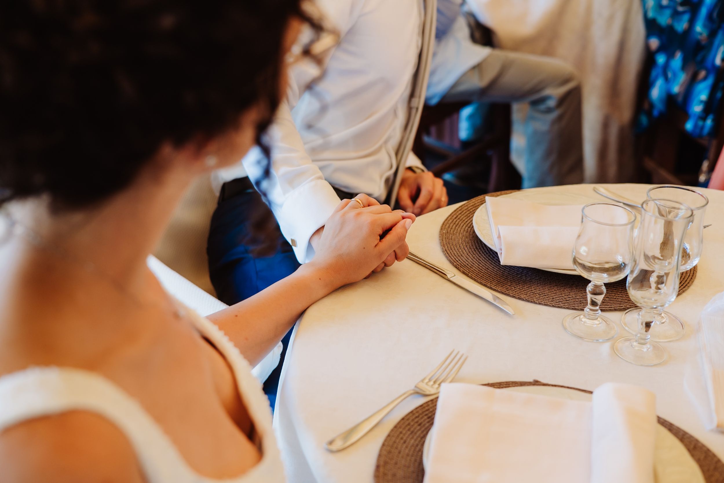 Place setting at an elegant wedding reception with white tablecloth and formal dinnerware.