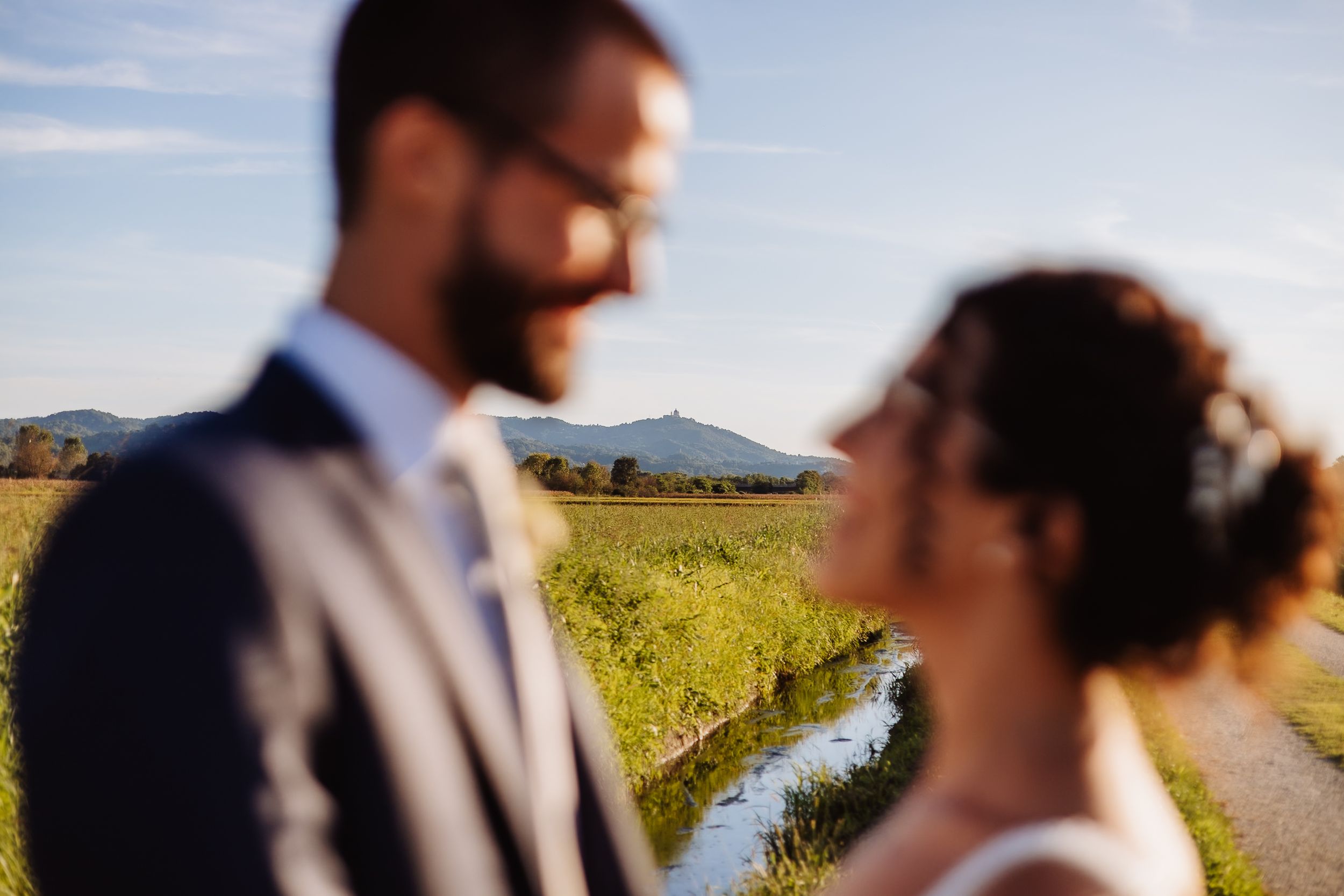 A couple shares an intimate moment in a scenic vineyard setting during golden hour.