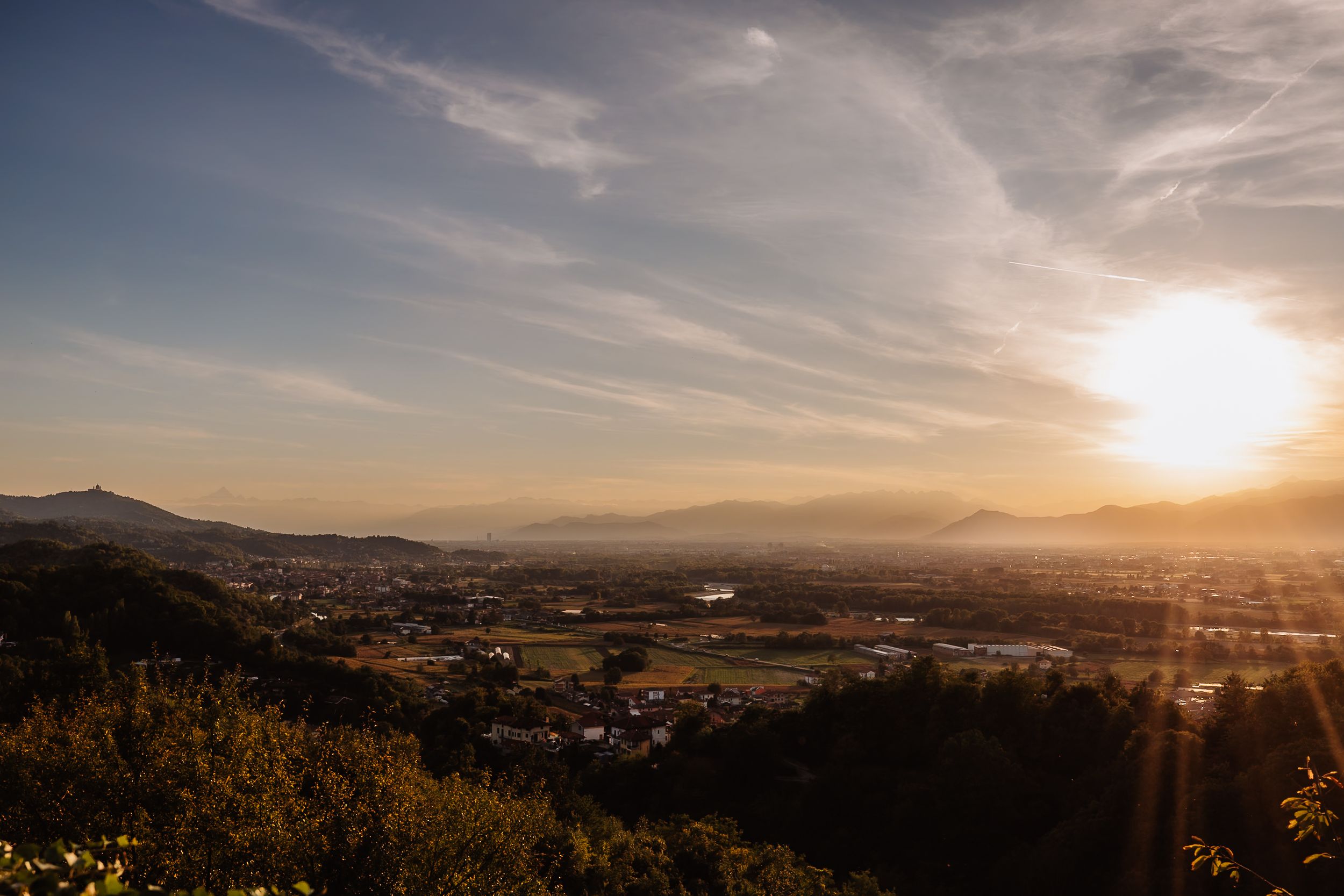 Scenic mountain landscape view at sunset with golden sunlight streaming over a valley and distant hills.